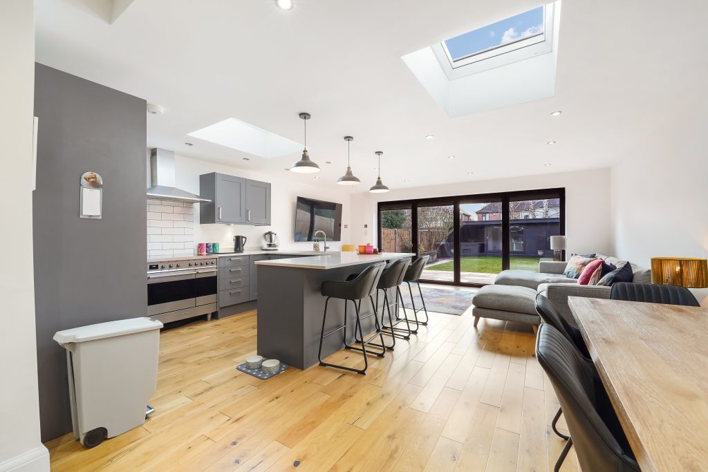 Modern kitchen and dining area with a central island, bar stools, and large windows providing natural light.